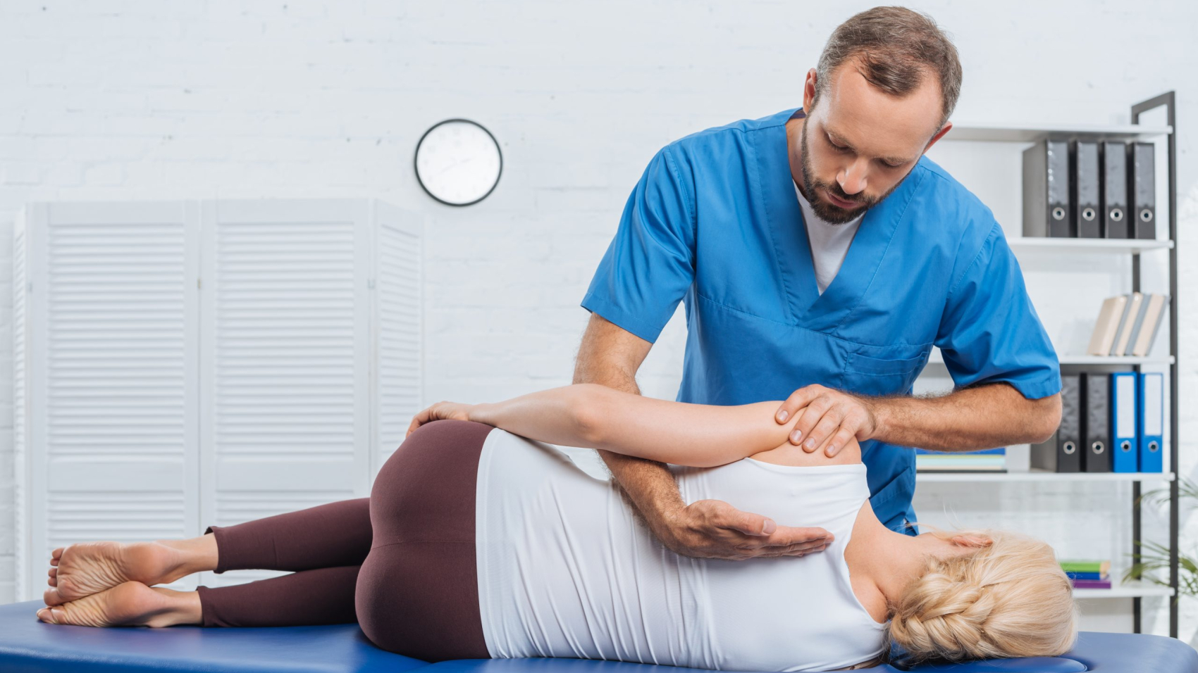 chiropractor massaging back of patient that lying on massage table in hospital