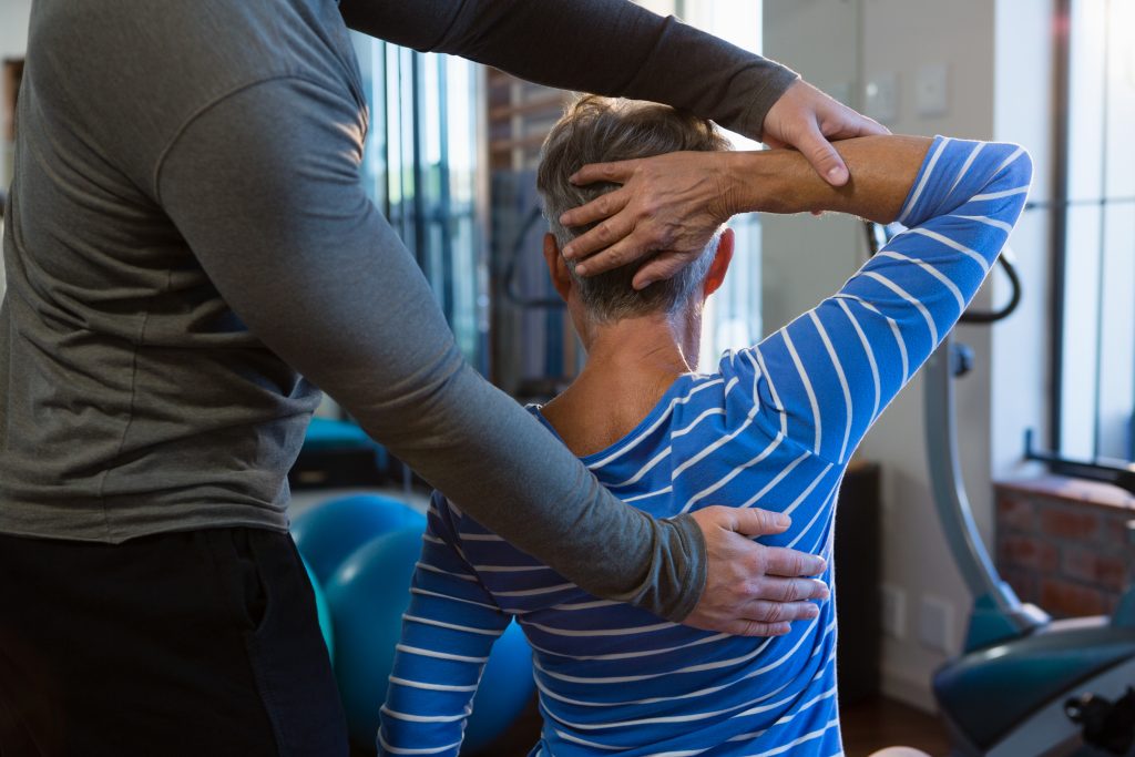 Chiropractor assisting woman in exercise at clinic.