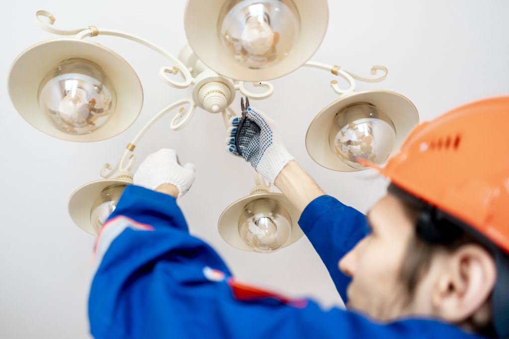 Electrician installing a new chandelier ina home
